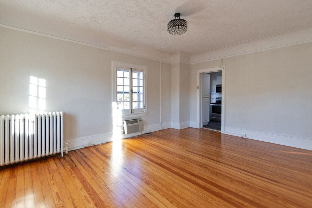 an empty living room with wood floors and a radiator