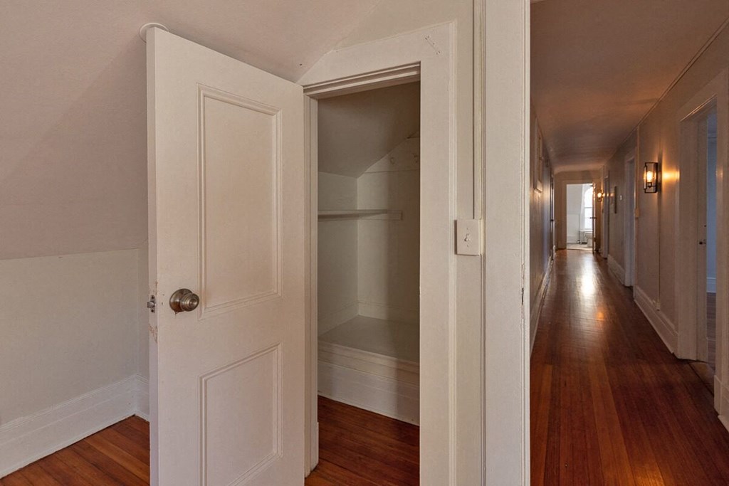 a hallway with a white door open to a closet