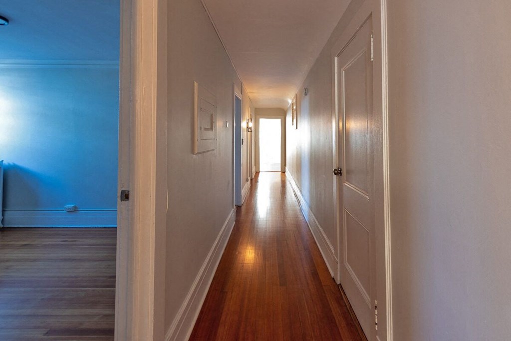 a hallway with wooden floors and a blue wall and white doors