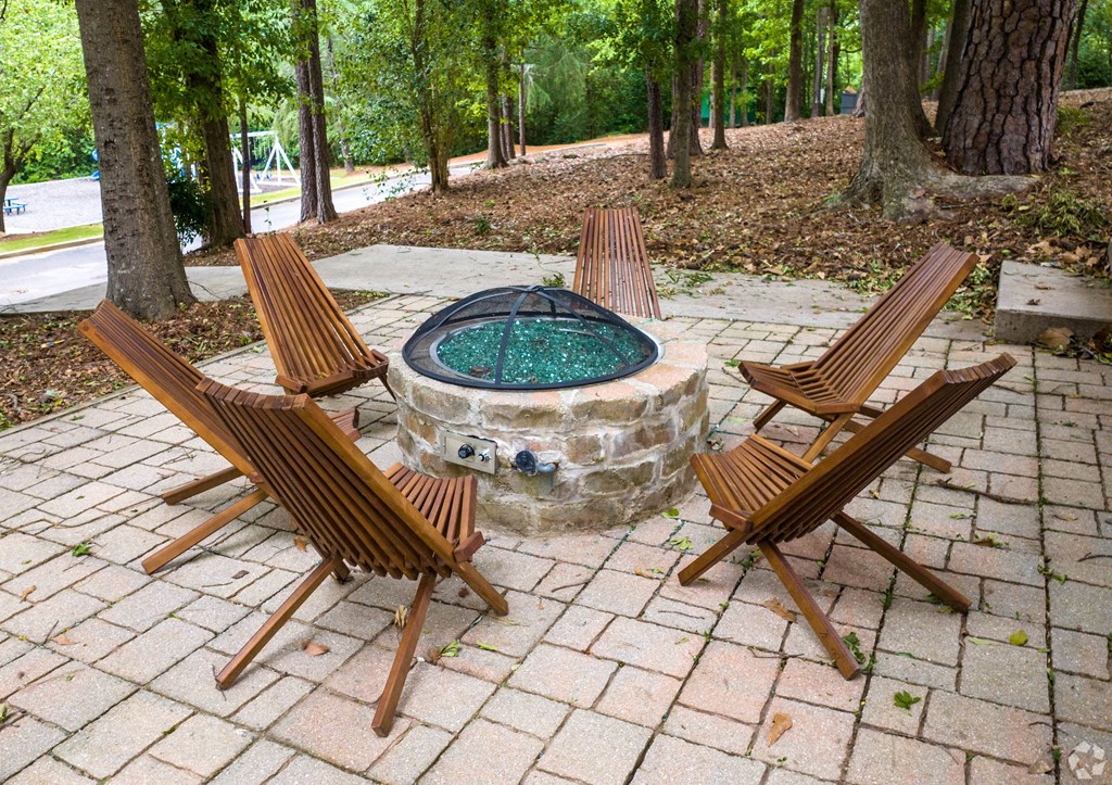 a stone firepit with wooden deck chairs around it