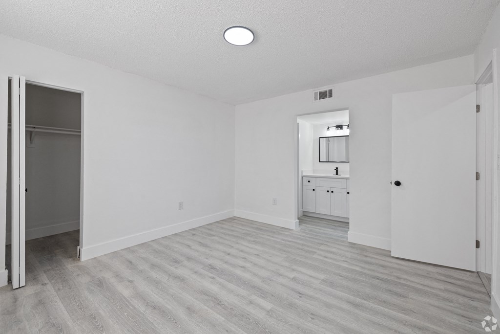 an empty living room and kitchen with white walls and wood flooring