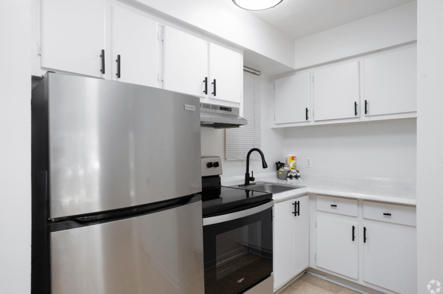 a kitchen with white cabinets and black appliances