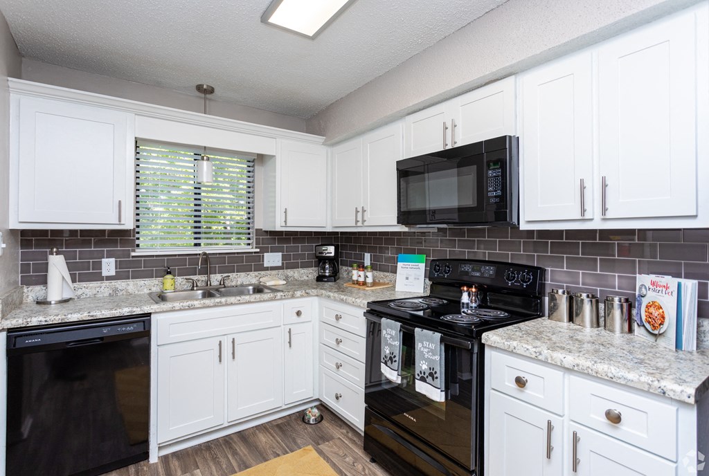 a kitchen with white cabinets and black appliances