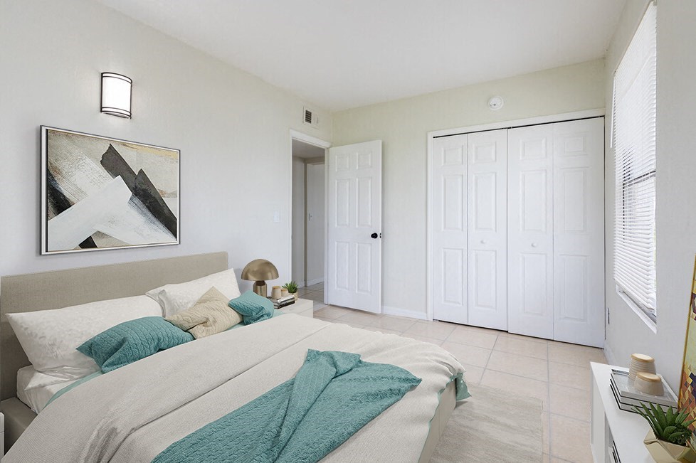 a bedroom with white walls and a white bed with green throw pillows