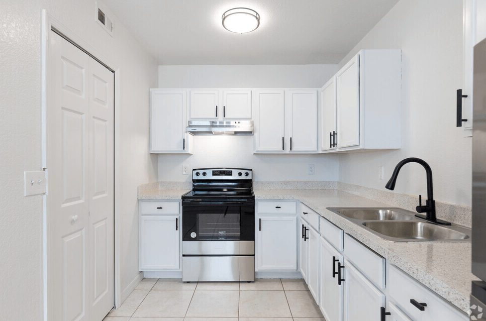 a kitchen with white cabinets and white tile flooring
