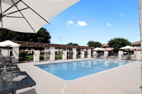 A pool surrounded by white umbrellas and chairs.
