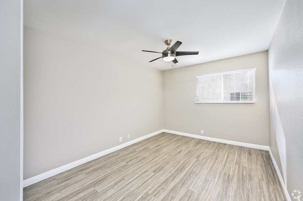 A room with a ceiling fan and a window with blinds.