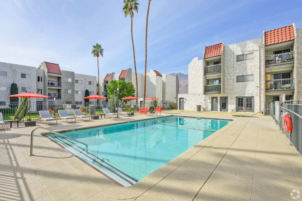 A swimming pool surrounded by palm trees and lounge chairs.