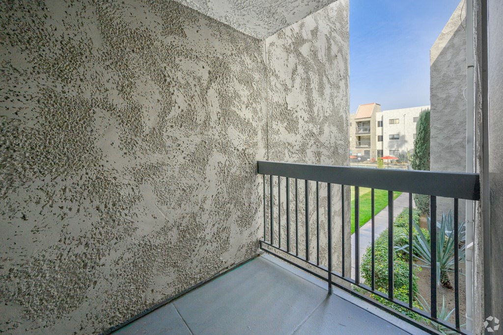 A balcony with a metal railing and a wall with a textured pattern.