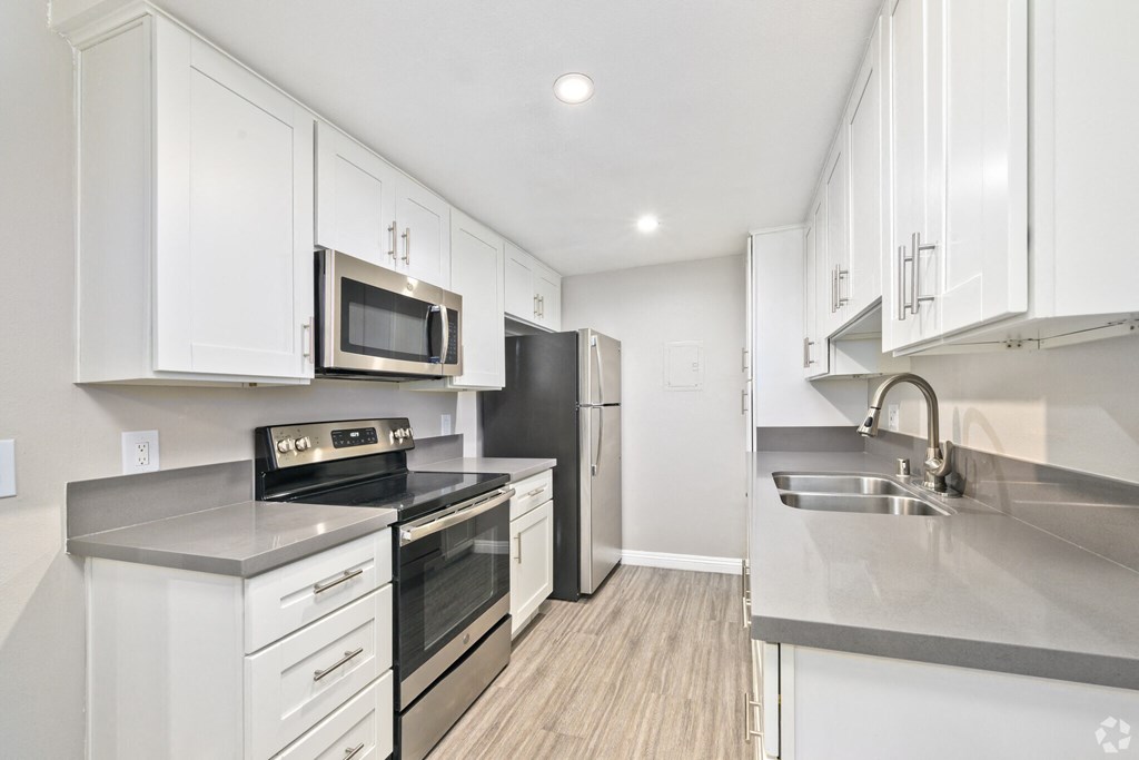 A modern kitchen with white cabinets and stainless steel appliances.