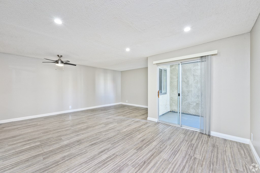 A room with a ceiling fan and sliding glass door.