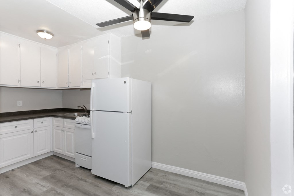 a white kitchen with white cabinets and a white refrigerator