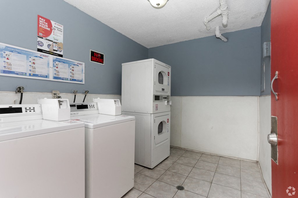 a laundry room with two washing machines and two refrigerators