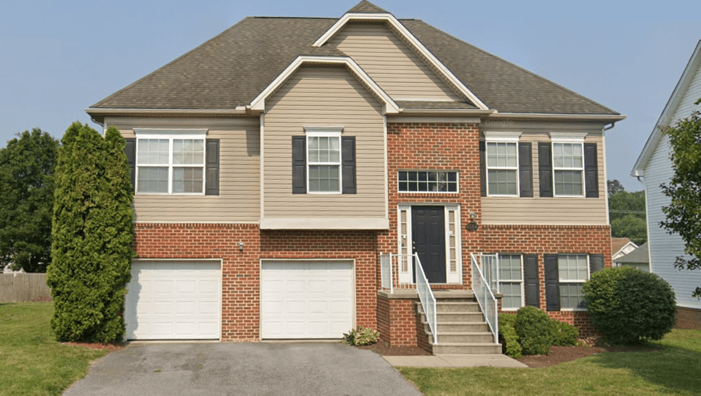 a house with two garage doors and a stair case in front of it