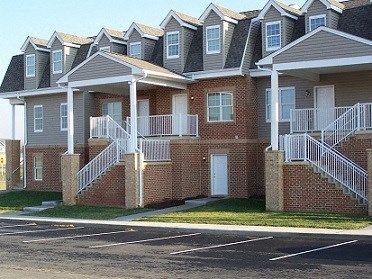 A row of houses with white railings and steps leading to the doors.