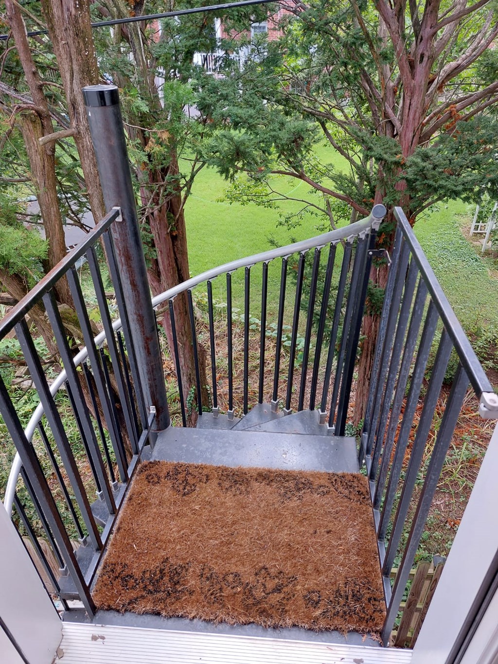 A metal staircase with a brown doormat on the bottom step.