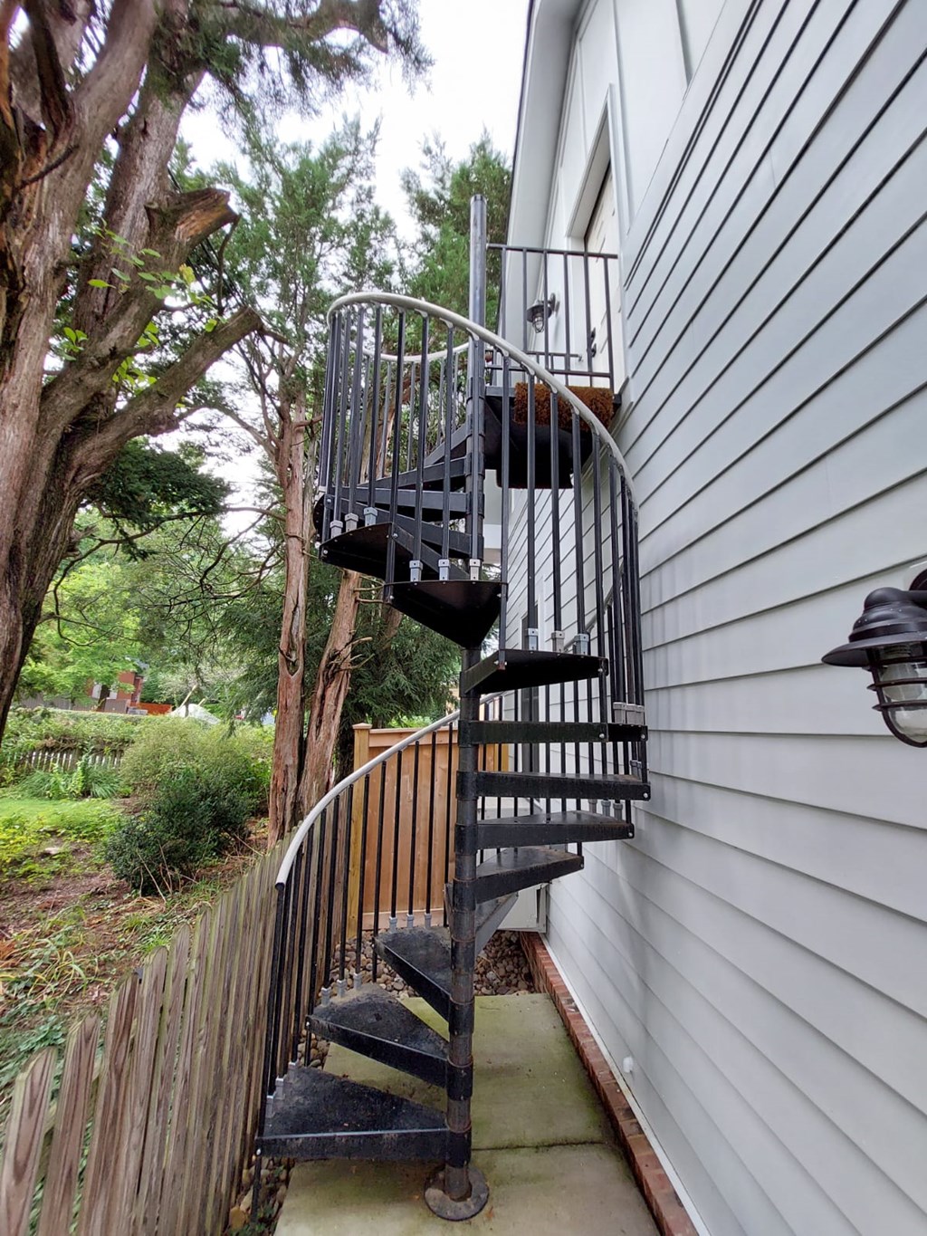 A spiral staircase with a metal railing is attached to a house.
