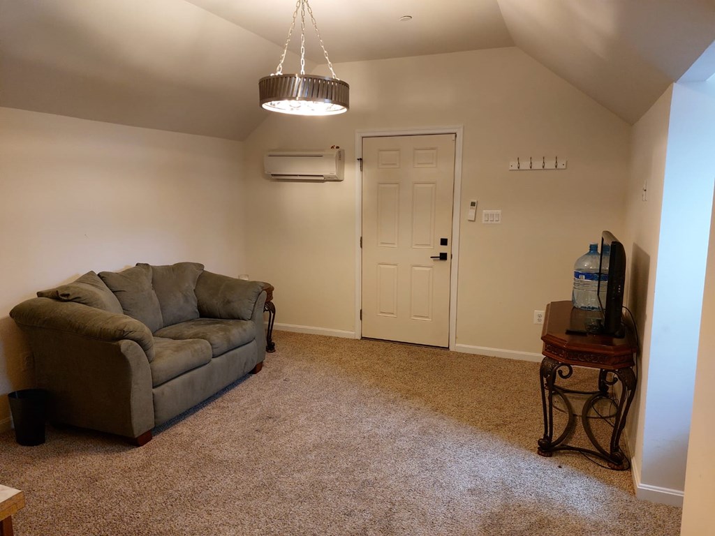 A living room with a grey couch and a table with a water bottle on it.