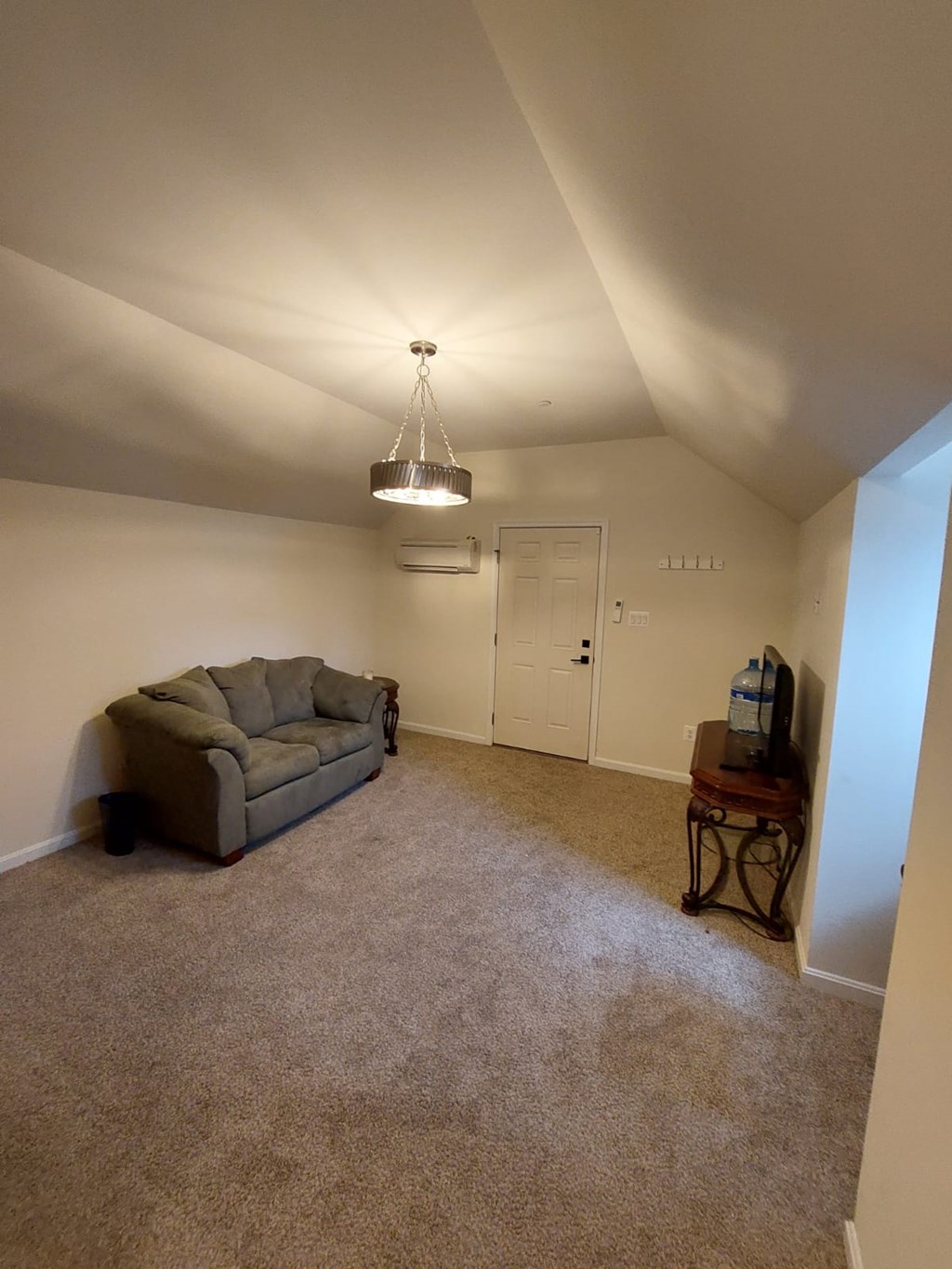 A living room with a grey couch and a hanging light fixture.