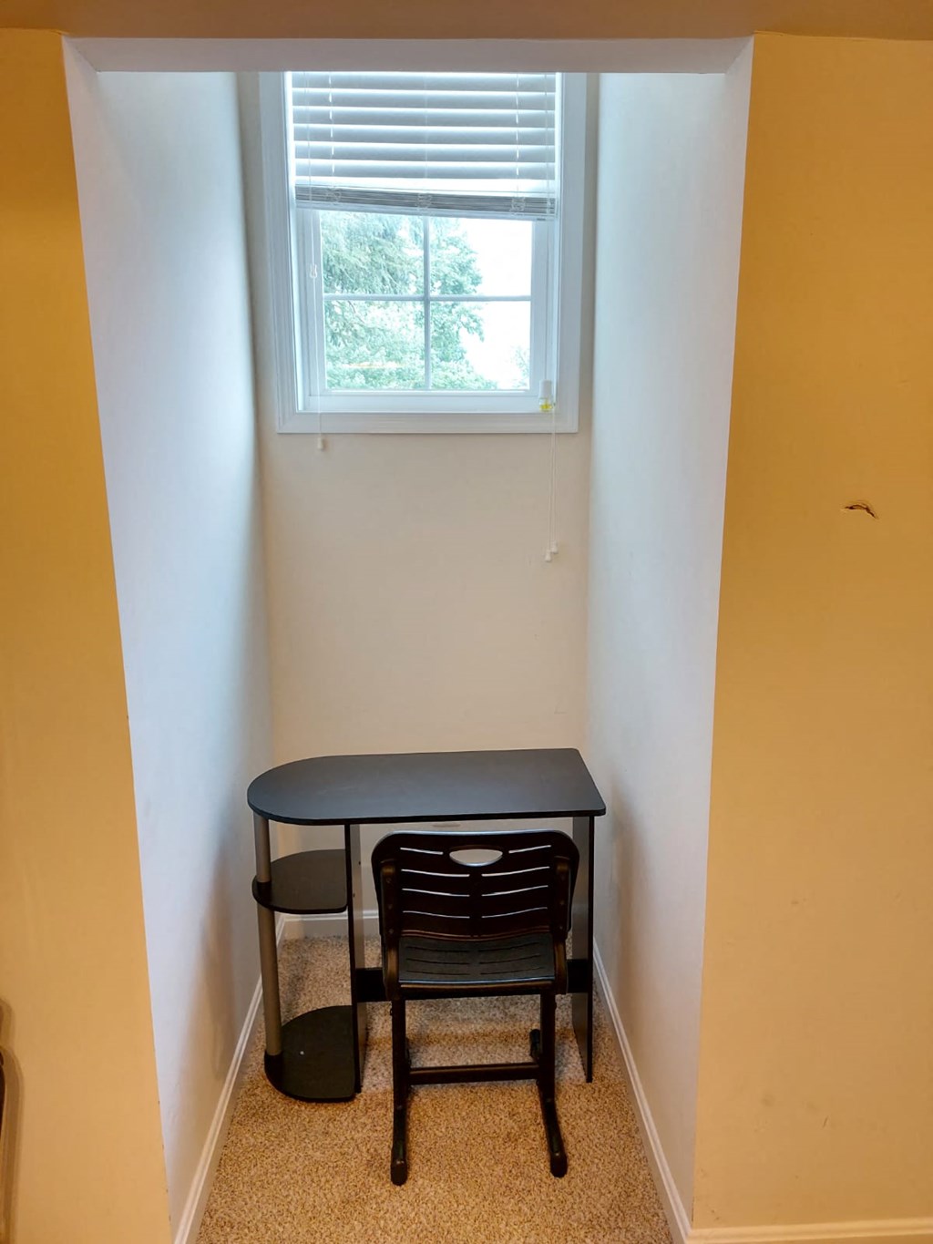 A black chair sits in front of a small table in a room with yellow walls.