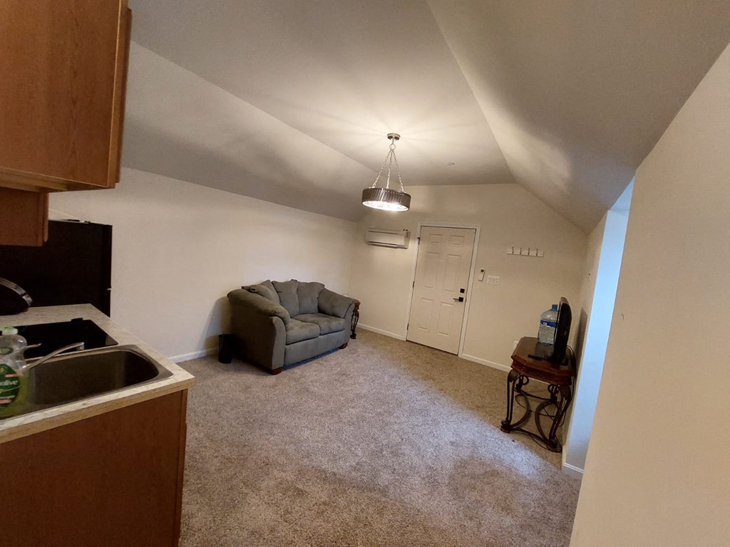 A kitchen with a sink and a grey couch in the living room.