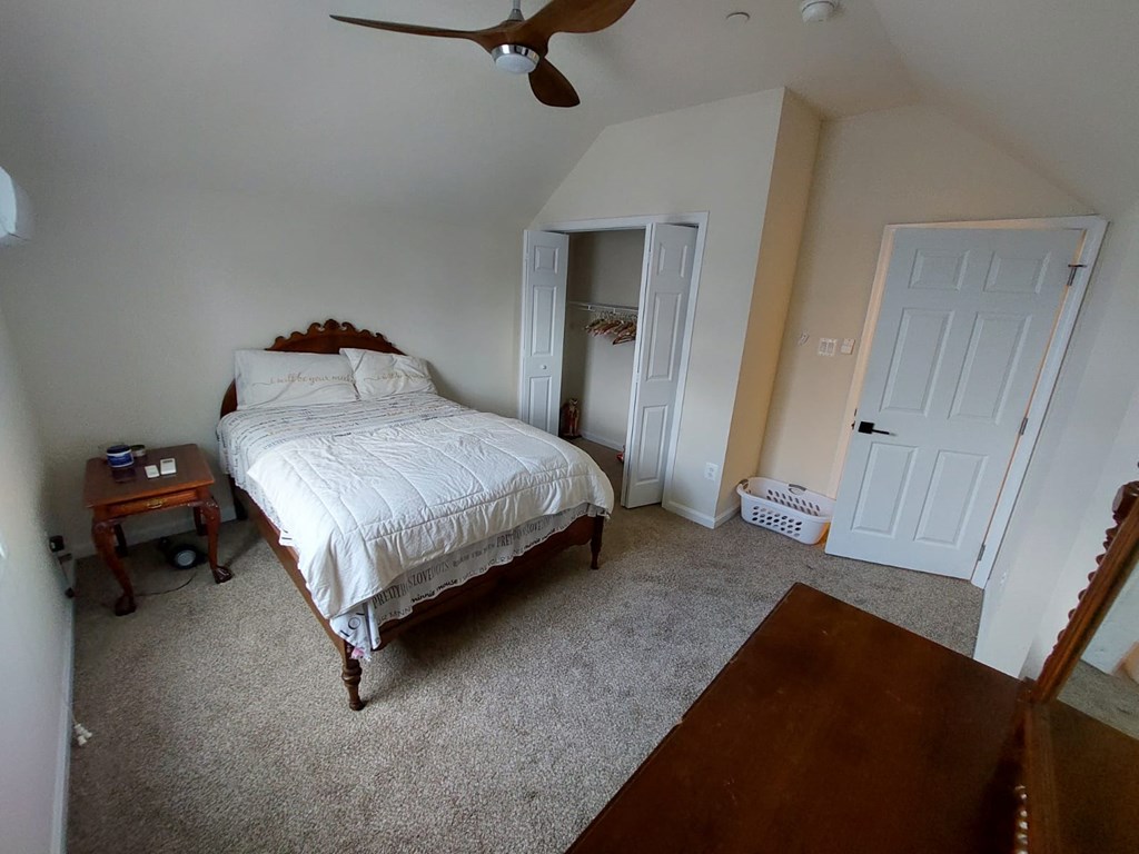 A bedroom with a bed, dresser, and ceiling fan.