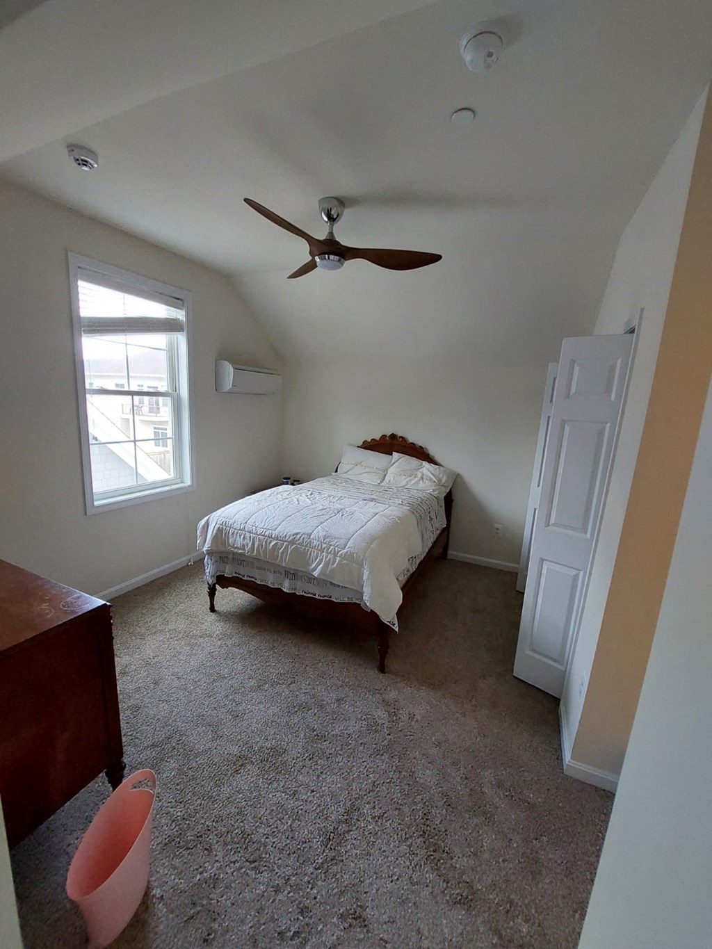 A bedroom with a bed, dresser, and window.