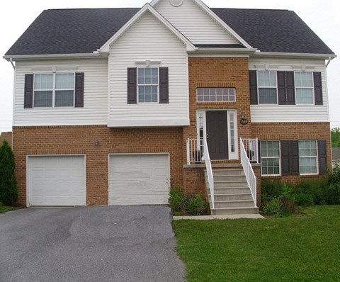 a brick house with two garage doors and a driveway