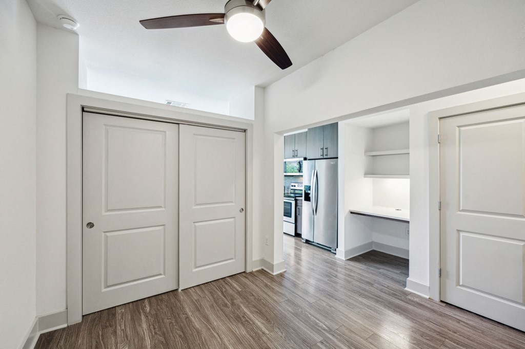 an empty living room with white doors and a ceiling fan