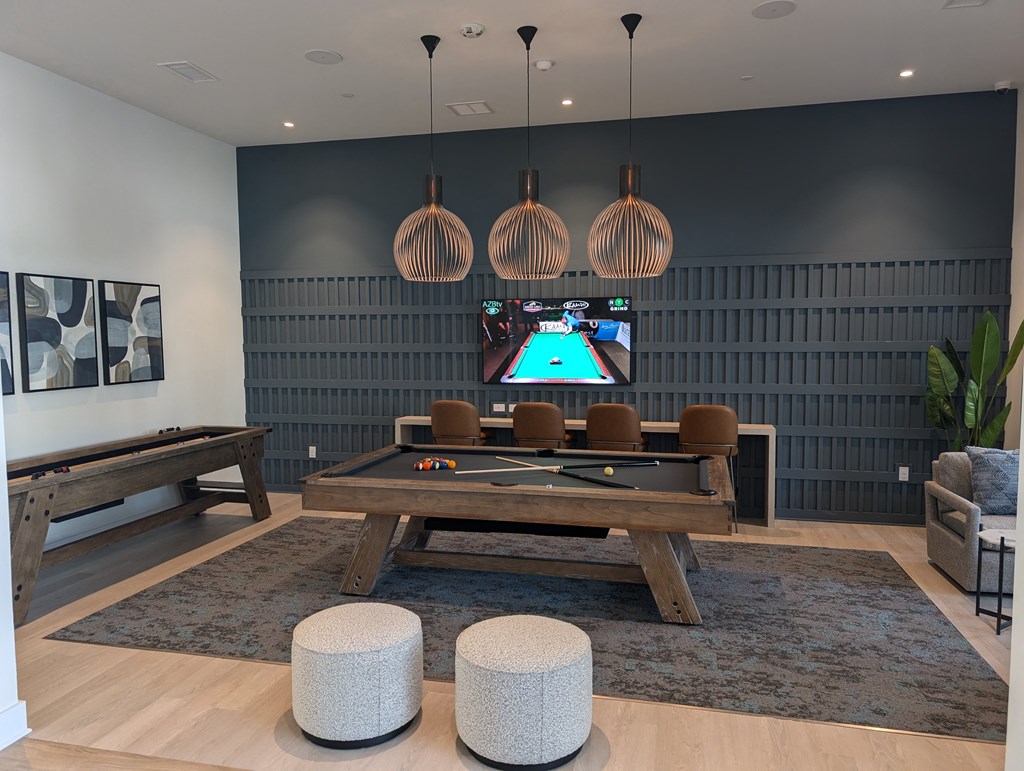 A room with a pool table and a TV mounted on the wall.