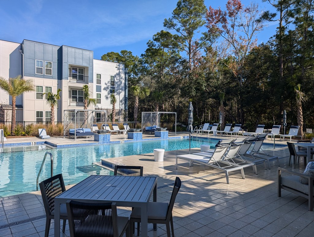 A pool area with chairs and a table in front of a building.
