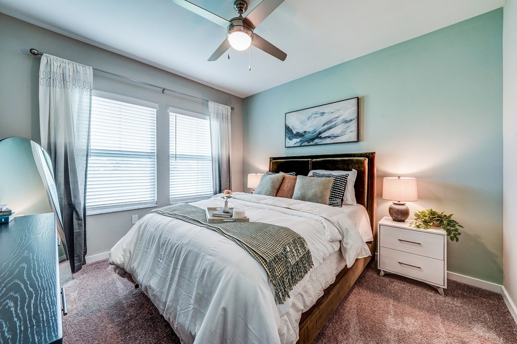 the master bedroom has a large window and a ceiling fan