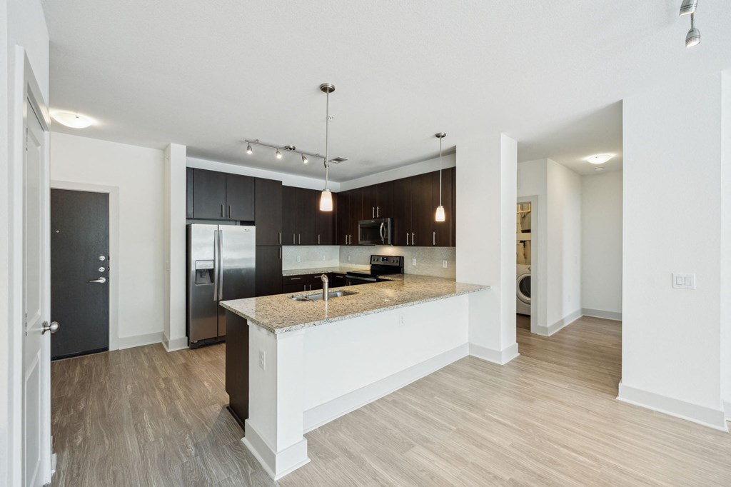 an open kitchen and living room with a marble counter top
