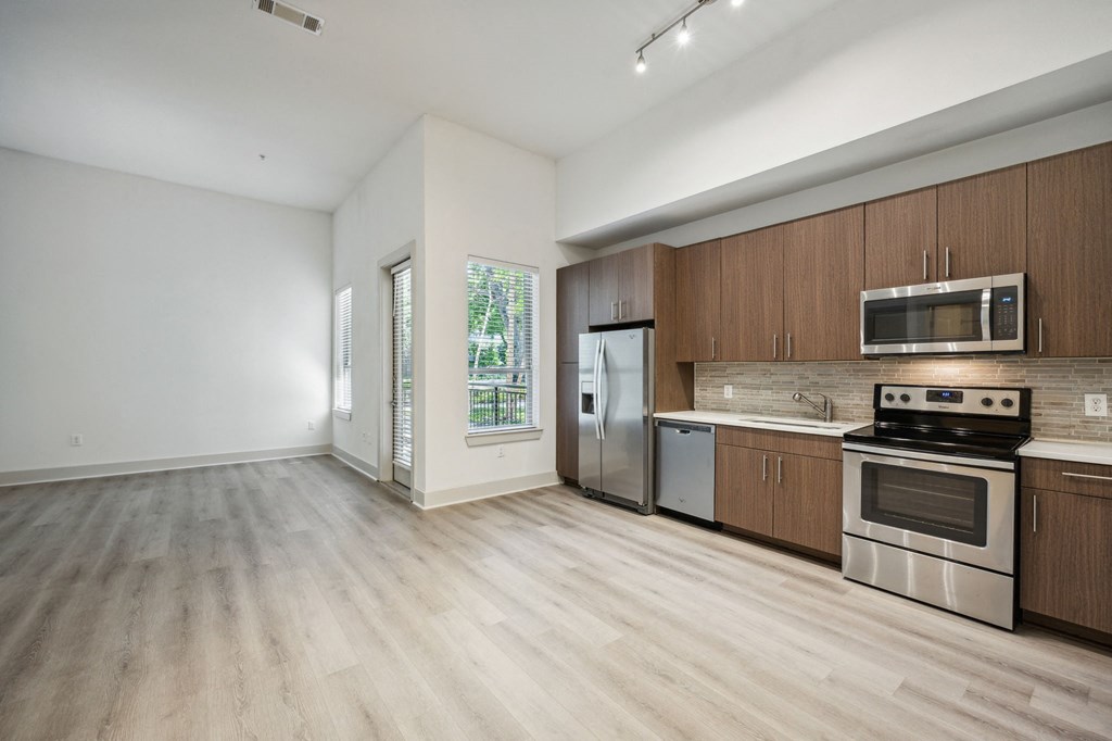 an empty kitchen with wooden cabinets and stainless steel appliances