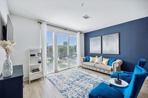 a living room with blue walls and a large window with a couch and a chair