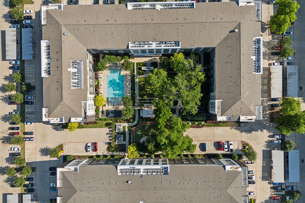 an overhead view of a building with trees and a pool