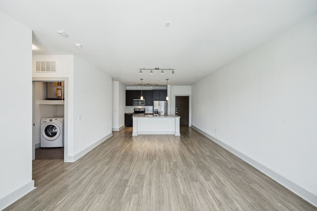a living room with a kitchen and a washer and dryer