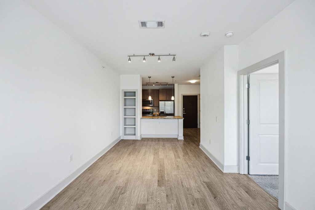 a living room and kitchen with white walls and wood floors