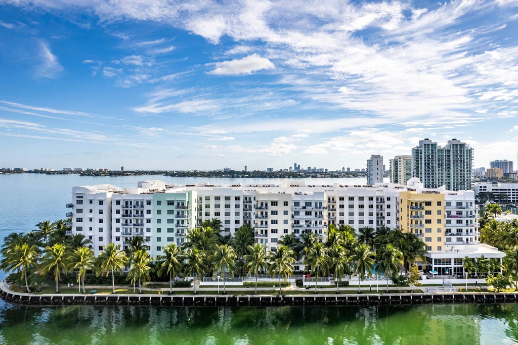 a large building with palm trees in front of a body of water