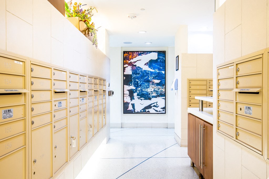 a long white hallway with wooden cabinets and a painting on the wall