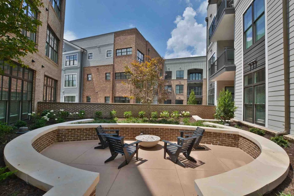 an outdoor patio with a firepit and chairs in front of an apartment building