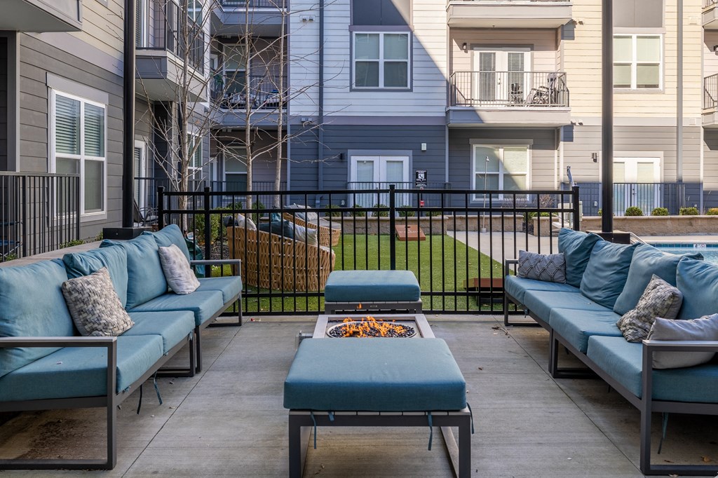 an outdoor patio with blue couches and a fire pit