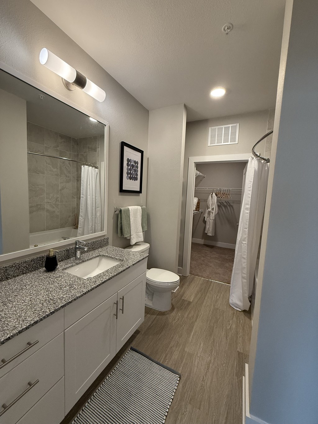 A bathroom with a sink, mirror, toilet, and shower.
