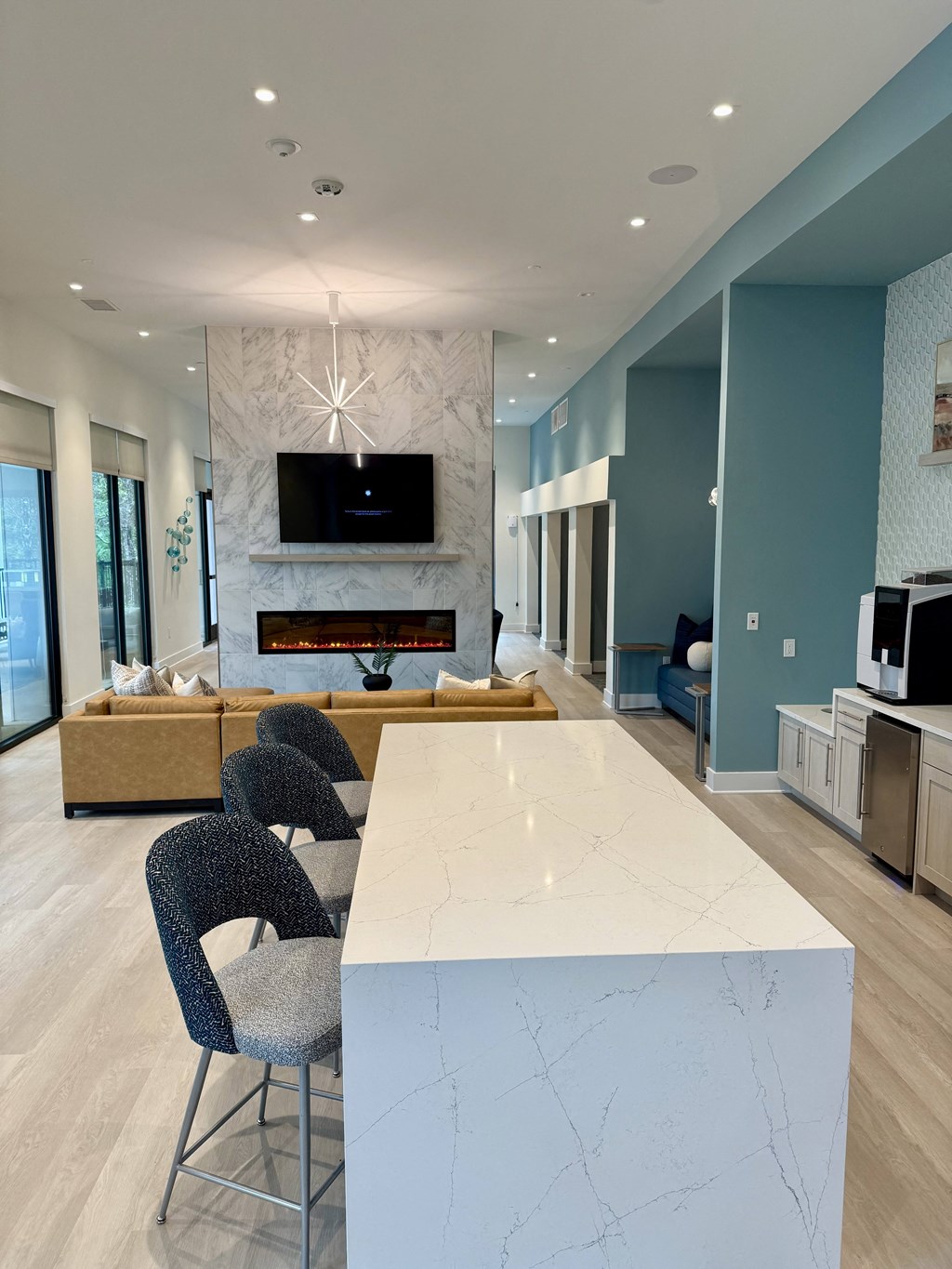A modern kitchen with a white marble island and a television mounted above it.