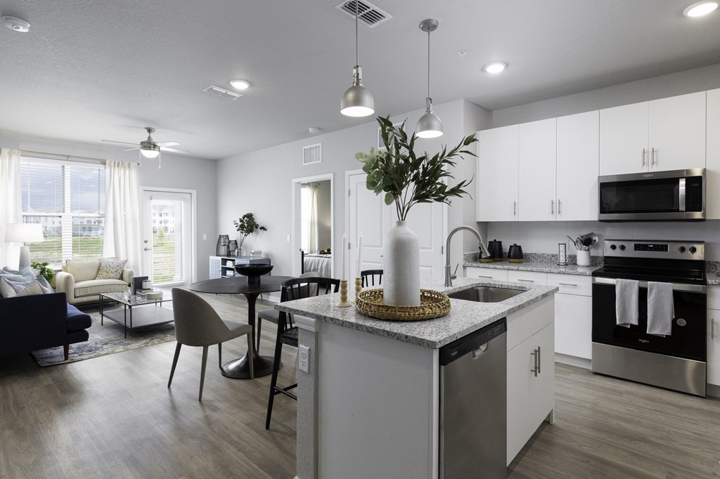 a kitchen and living room with white cabinets and a counter top