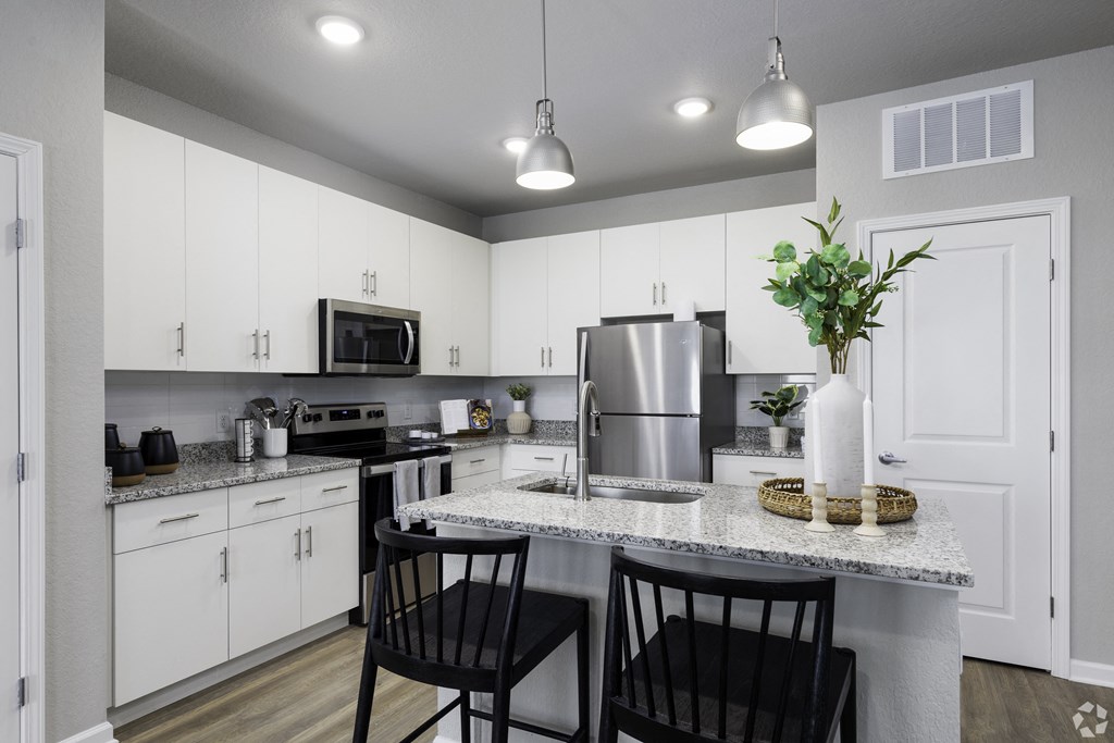 an open kitchen with white cabinets and a granite counter top
