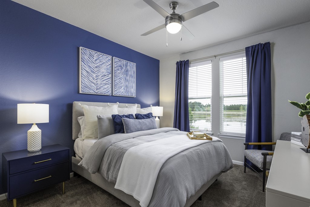 a blue and white bedroom with a bed and a ceiling fan