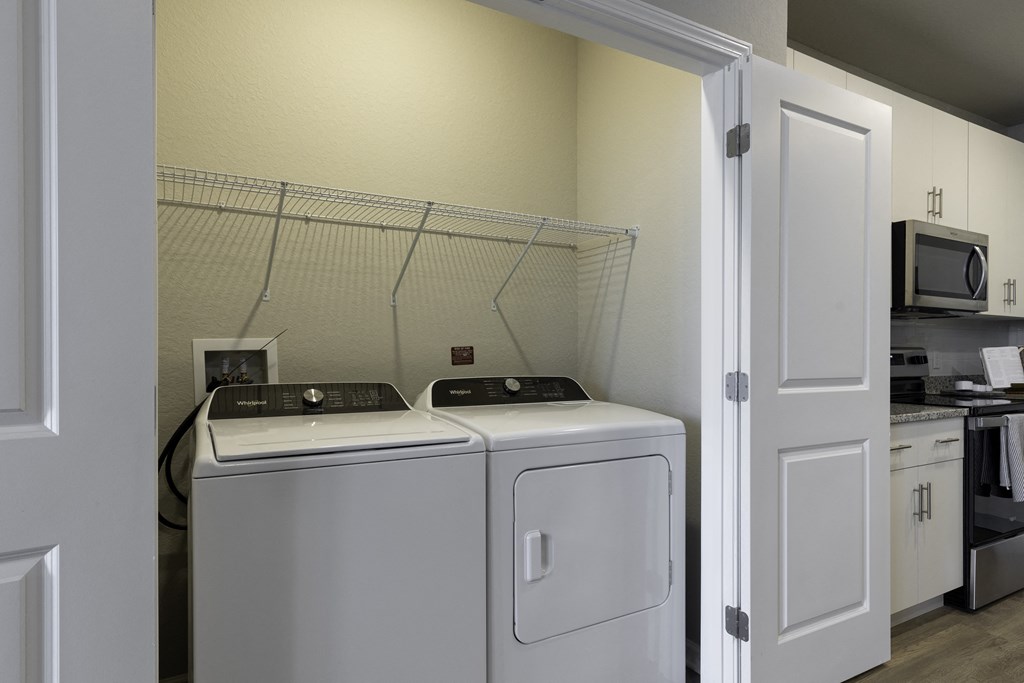 a washer and dryer in a laundry room with a kitchen in the background