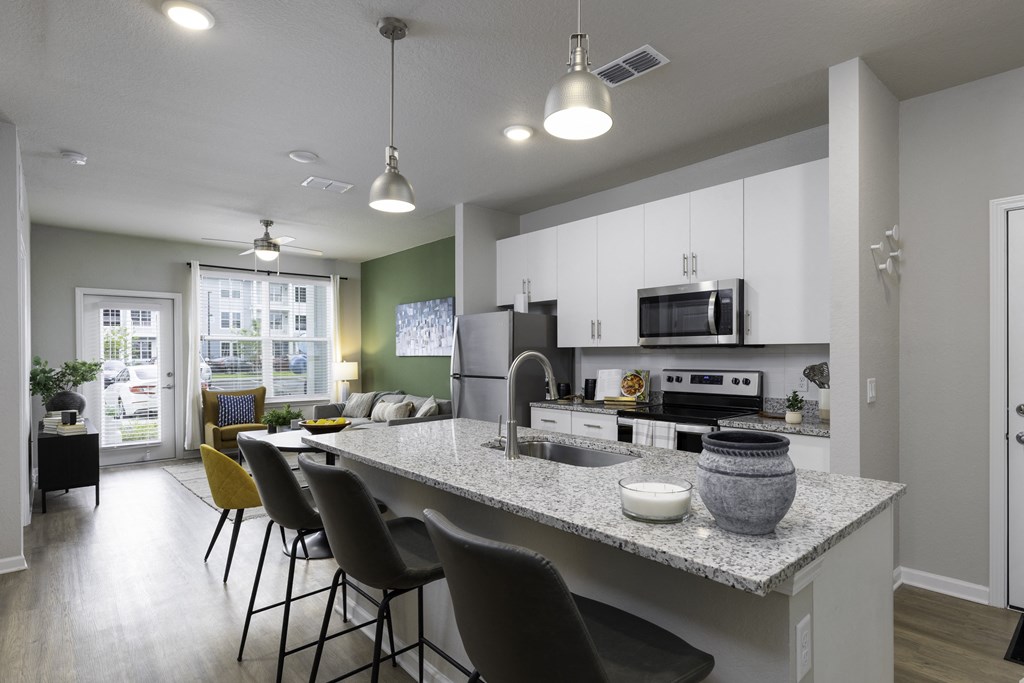 an open kitchen and living room with a granite counter top