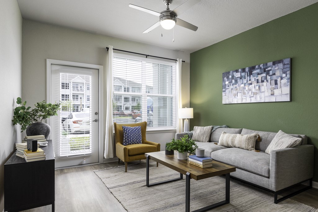 a living room with green walls and a ceiling fan